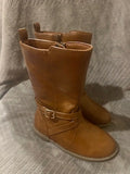 Pair of brown leather boots with buckles on a light gray background