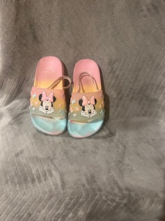 Pair of colorful slippers with cartoon character design on a gray surface