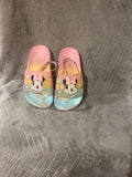 Pair of colorful slippers with cartoon character design on a gray surface